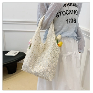 Detailed view of white lace tote bag with floral patterns and woven texture finish