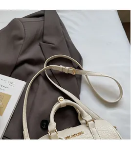Detail of elegant crocodile-embossed pillow bag with gold hardware and logo plaque