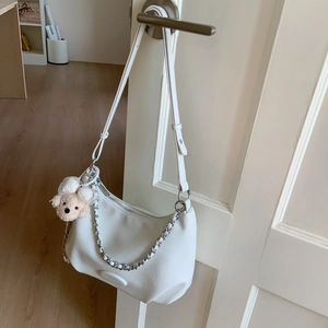 Detail of white leather shoulder bag with plush bear charm and silver metal chain