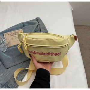 Broderie détaillée de lettres roses sur un sac banane en toile jaune clair avec zip