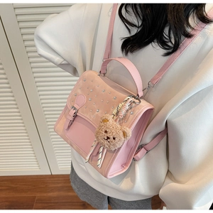 Detail view of pink leather backpack with diamond embellishment and brown plush bear charm
