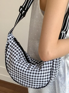 Gingham patterned dumpling bag with a striped wide strap shown on a model