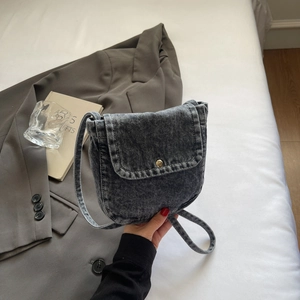 Close-up of vintage grey denim crossbody bag with metal magnetic snap closure