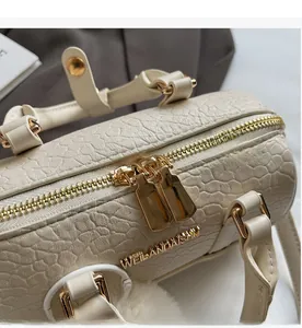 Close-up of the smooth golden double zipper detail on a beige leather Boston bag