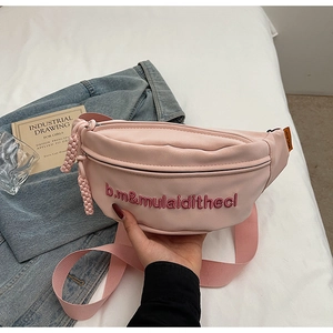 Détail du sac bandoulière rose avec broderie de lettres et texture en cuir souple