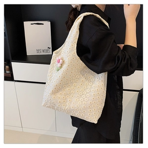 Detail of floral lace embroidery canvas tote bag with a pink plush flower pendant