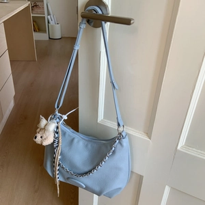 Detail of light blue crescent bag with silver zipper, chain, and plush puppy charm