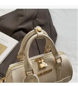 Detail of cream pillow bag featuring crocodile texture leather and gold metal zippers