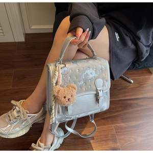 Detailed shot of silver satin bag with star prints, rhinestones and bear charm