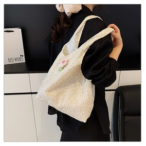 Close-up of white lace tote bag with floral embroidery and green flower pendant charm