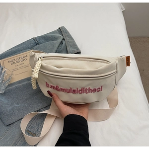 Détail du sac bandoulière beige avec broderie rose et fermeture éclair tissée sur lin