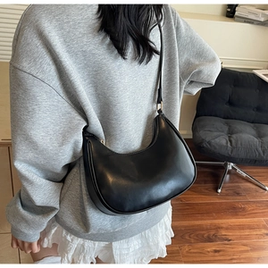 Close-up of a black crescent hobo bag made of smooth leather with adjustable strap
