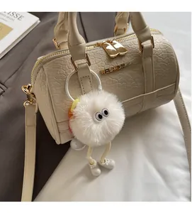 Detailed macro view of white crocodile pattern pillow bag with plush monster charm and gold hardware