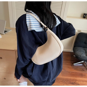 Minimalist beige hobo bag styled with a blue shirt and striped shawl in an office setting