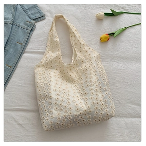 Detailed close-up of beige lace tote bag featuring 3D daisy floral embroidery and texture