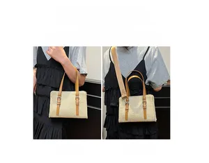 Detail of hand-woven straw bag featuring brown leather handles and adjustable shoulder strap