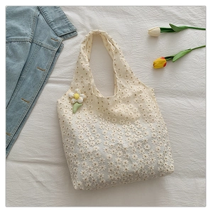 Detailed macro view of beige canvas tote bag with floral embroidery and 3D flower charm