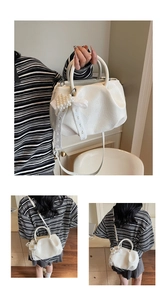 Close-up of white pleated small square handbag featuring elegant pearl bow accessory
