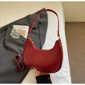 Detail of burgundy semi-circle leather bag with gold hardware and adjustable strap