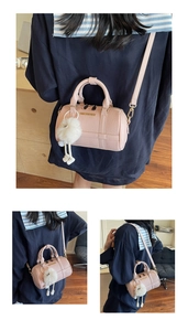 Close-up of pink Boston bag with lychee texture, gold logo, and white plush charm detail