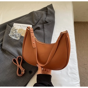 Detailed view of caramel half-moon faux leather bag with adjustable long shoulder strap