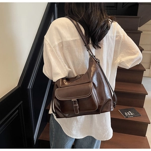 Deep brown leather tote bag detail with decorative front pocket and white stitching accents