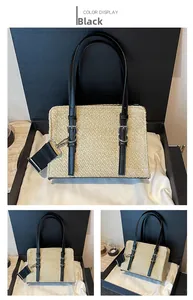 Detail view of woven beige straw bag with black handles and detachable nylon strap