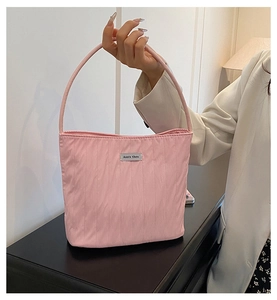 Detail of pink pleated tote bag featuring a silver brand label and silk-like texture