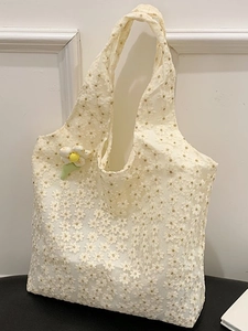 Off-white lace tote bag with floral embroidery and a small daisy charm accessory