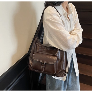 Detail view of large brown tote bag with white contrast stitching and pocket