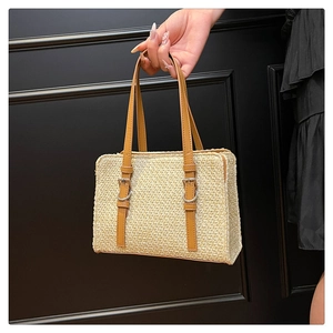 Detail of woven straw handbag with brown leather strap and silver metal buckle