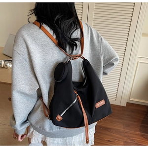 Detail view of stylish black nylon backpack with brown leather strap on model's back