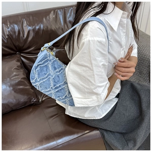 Detail of light blue denim hobo bag with frayed diamond quilting and gold zipper accents