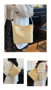 Detail view of the cream pleated tote bag featuring a textured fabric and woven logo label