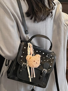 Fashionable black leather square bag with white pearl accents and a cute plush bear charm