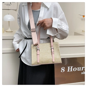 Detail of straw woven crossbody bag with pink leather trim and adjustable strap
