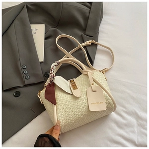 Détail du sac tressé avec foulard en soie décoratif et fermoir métallique doré chic