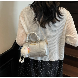 Rear view of silver metallic textured handbag with plush charm and long strap