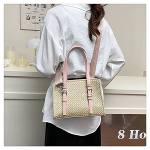 Close-up of woven straw handbag with pink leather trim and adjustable fabric strap