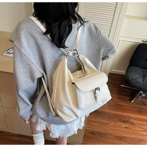 Chic off-white large capacity hobo backpack with buckle detail worn on model's back