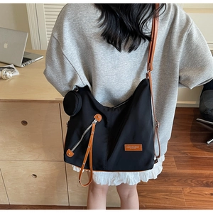 Detail of black nylon tote bag featuring brown leather trim and detachable coin purse