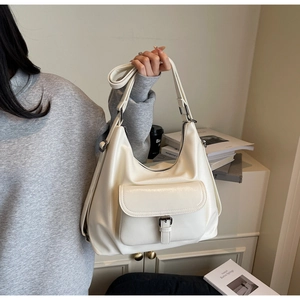 Detail of minimalist beige tote bag showing flap pocket, metal buckle and soft PU texture