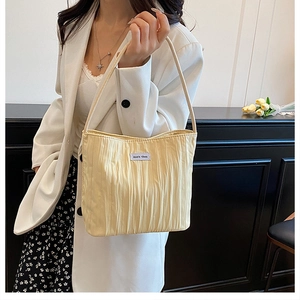Detail shot of pleated cream canvas tote bag with woven label and long handle strap