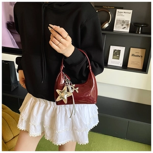 Detail of burgundy patent leather hobo bag with star and balloon dog charms
