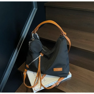 Detail of black nylon tote bag with brown leather handles and side coin pouch on stairs