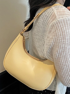 Minimalist cream crescent shoulder bag in smooth PU leather worn by a model