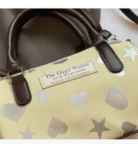 Dettaglio della borsa Boston con tessuto twill, cuori e stelle e manico in pelle marrone
