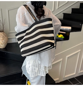 Détail du sac cabas en maille tissée à rayures noires et blanches et anses en cuir
