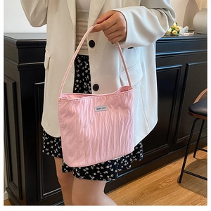 Detail of light pink pleated tote bag with woven label and comfortable long handles