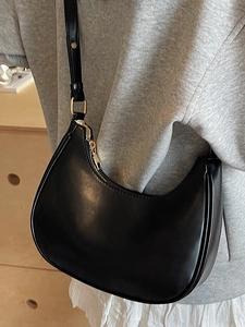 Minimalist black matte leather crescent underarm bag with gold zipper and adjustable strap